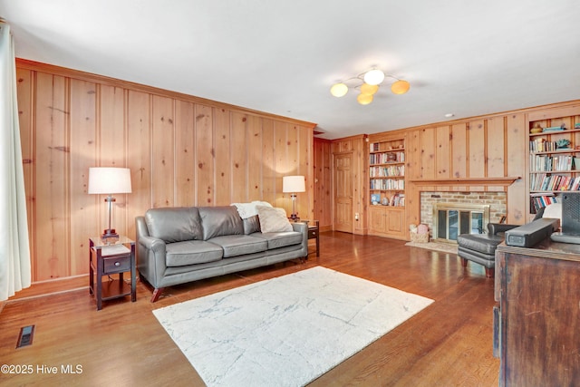 1714 E Walnut St, Goldsboro, NC 27530 - living room featuring wood walls, built in shelves, a fireplace, and wood finished floors