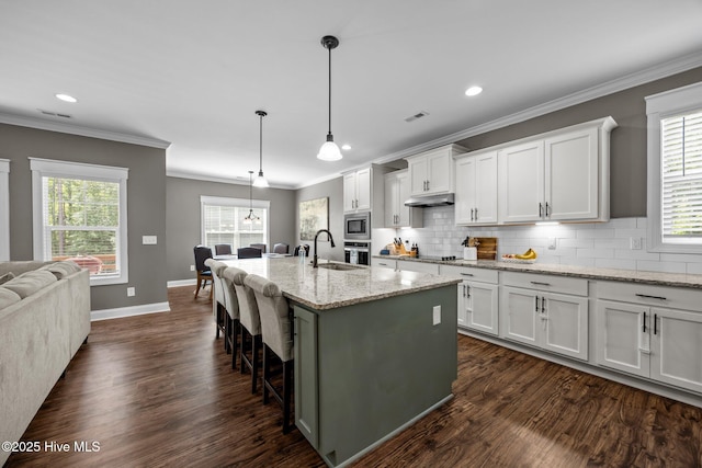 28 Winding Trl, Whispering Pines, NC 28327 - kitchen with stainless steel microwave, ornamental molding, dark wood-type flooring, white cabinets, and tasteful backsplash