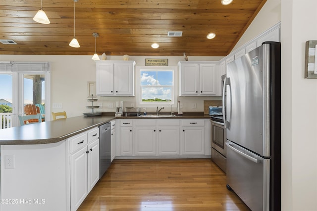 110 Mangrove Blvd, Emerald Isle, NC 28594 - kitchen featuring stainless steel appliances, a peninsula, dark countertops, wood ceiling, and white cabinets
