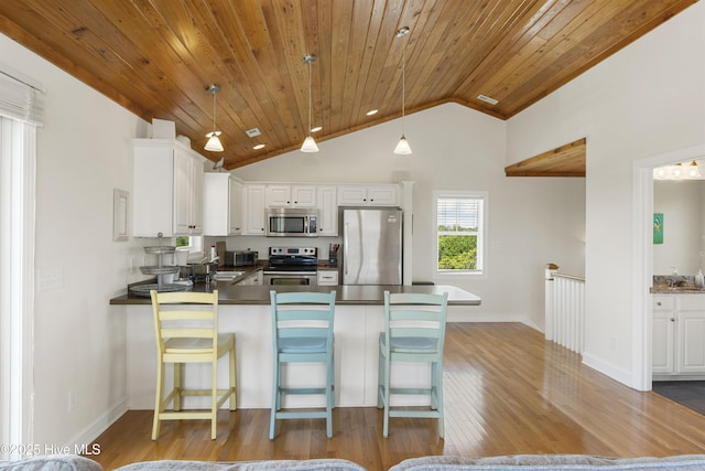 110 Mangrove Blvd, Emerald Isle, NC 28594 - kitchen featuring stainless steel appliances, a peninsula, light wood-style flooring, wood ceiling, and white cabinetry