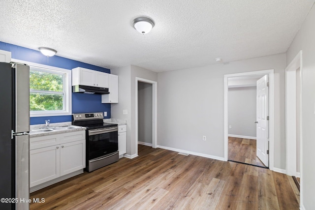 1415 Glenn St, Wilmington, NC 28401 - kitchen featuring stainless steel appliances, under cabinet range hood, white cabinetry, light countertops, and wood finished floors