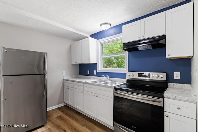 1415 Glenn St, Wilmington, NC 28401 - kitchen with appliances with stainless steel finishes, under cabinet range hood, light countertops, white cabinets, and a textured ceiling