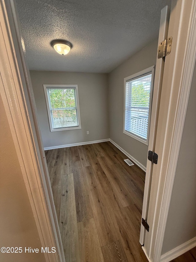 1415 Glenn St, Wilmington, NC 28401 - unfurnished room featuring healthy amount of natural light, dark wood-style floors, and a textured ceiling