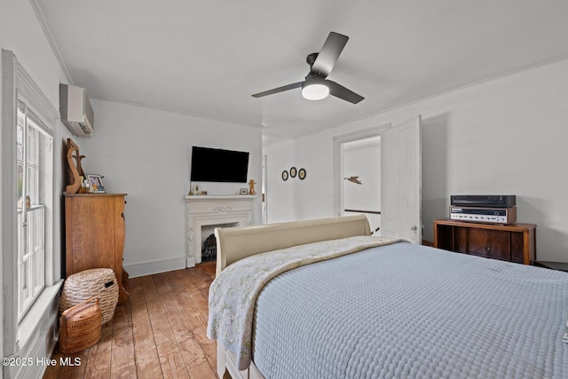 409 Hancock St, New Bern, NC 28560 - bedroom with a wall mounted AC, hardwood / wood-style floors, a ceiling fan, and a fireplace