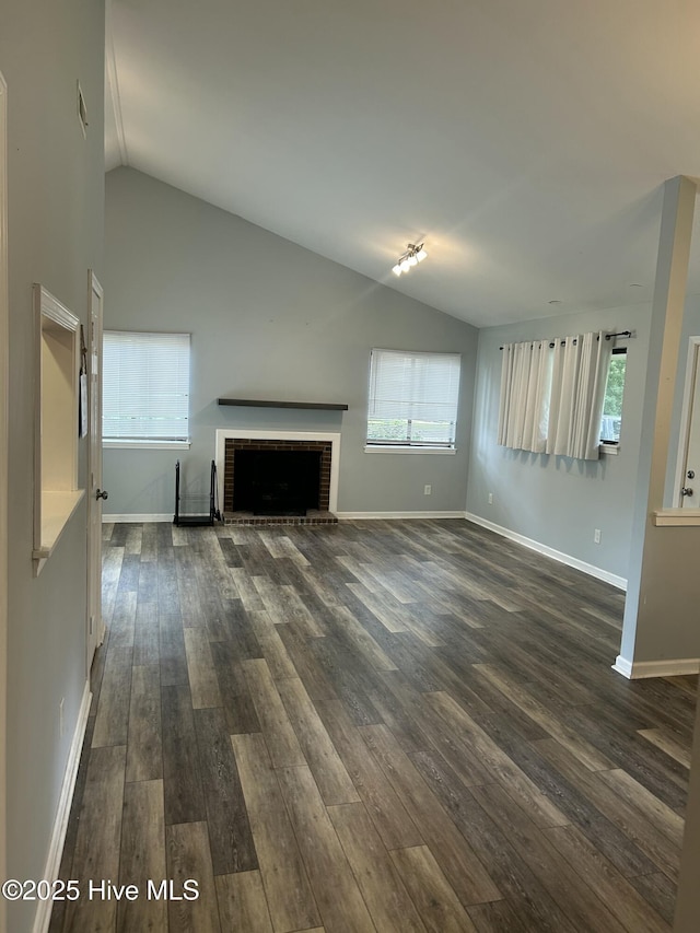 106 Quarterdeck Townes Townes Unit 106, New Bern, NC 28562 - unfurnished living room featuring vaulted ceiling, dark wood-style flooring, healthy amount of natural light, and a brick fireplace