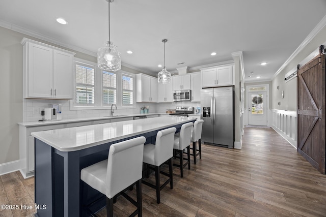 184 Twining Rose Ln, Holly Ridge, NC 28445 - kitchen featuring appliances with stainless steel finishes, a barn door, ornamental molding, a kitchen island, and white cabinetry