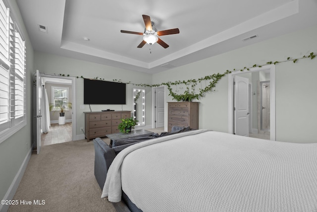 184 Twining Rose Ln, Holly Ridge, NC 28445 - bedroom with a raised ceiling, light carpet, ensuite bath, and ceiling fan