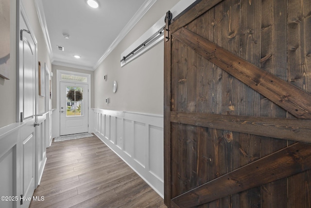 184 Twining Rose Ln, Holly Ridge, NC 28445 - doorway featuring a barn door, ornamental molding, wainscoting, a decorative wall, and wood finished floors