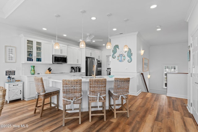 328 E First St, Ocean Isle Beach, NC 28469 - kitchen featuring stainless steel appliances, light countertops, wood finished floors, a breakfast bar area, and recessed lighting