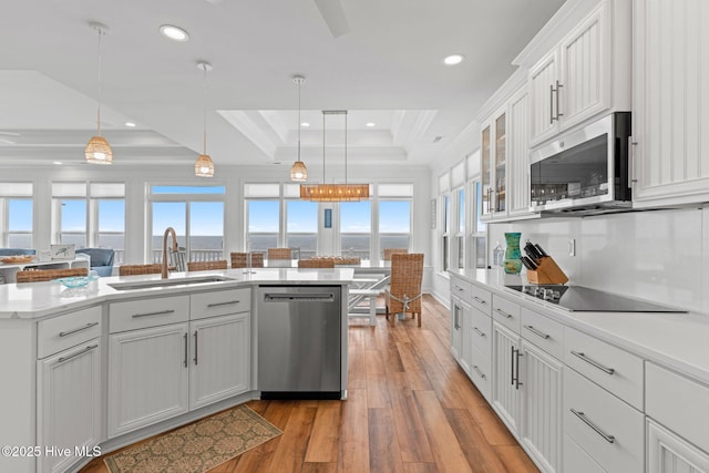 328 E First St, Ocean Isle Beach, NC 28469 - kitchen featuring stainless steel appliances, a tray ceiling, light wood finished floors, pendant lighting, and recessed lighting