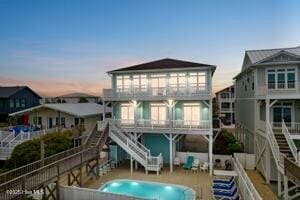 328 E First St, Ocean Isle Beach, NC 28469 - back of house at dusk featuring stairway and a patio area