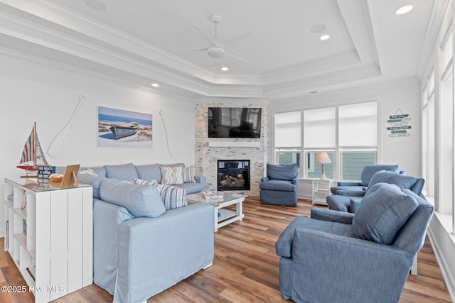 328 E First St, Ocean Isle Beach, NC 28469 - living area featuring a raised ceiling, a glass covered fireplace, a ceiling fan, wood finished floors, and crown molding