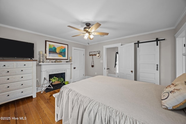 209 E Main St, Washington, NC 27889 - bedroom featuring crown molding, wood finished floors, a barn door, a fireplace with flush hearth, and ceiling fan