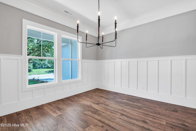 5988 Gray Squirrel Path, Southport, NC 28461 - empty room featuring a chandelier, a decorative wall, dark wood-style flooring, and a wainscoted wall