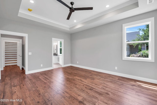 5988 Gray Squirrel Path, Southport, NC 28461 - unfurnished bedroom featuring a tray ceiling, multiple windows, hardwood / wood-style flooring, and recessed lighting