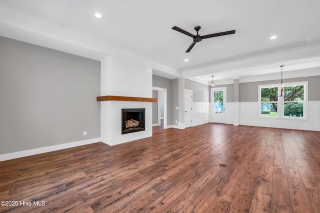 5988 Gray Squirrel Path, Southport, NC 28461 - unfurnished living room featuring a ceiling fan, dark wood-type flooring, a wainscoted wall, a fireplace, and recessed lighting