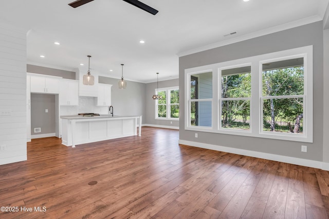 5988 Gray Squirrel Path, Southport, NC 28461 - unfurnished living room with wood-type flooring, crown molding, recessed lighting, and ceiling fan