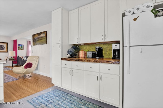 606 Ivey Cir, Wilmington, NC 28401 - kitchen featuring freestanding refrigerator, white cabinetry, tasteful backsplash, tile patterned flooring, and dark stone counters