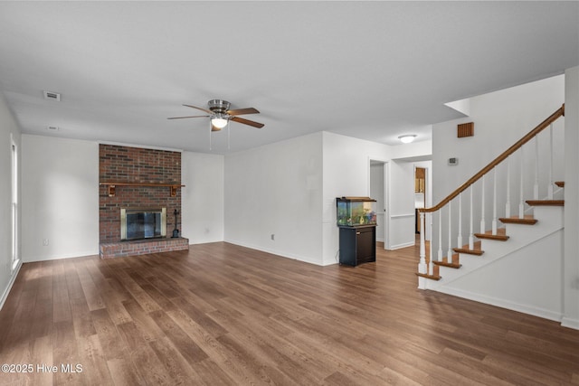 2544 Blake Trl, Wilmington, NC 28409 - unfurnished living room featuring wood finished floors, a ceiling fan, stairway, and a brick fireplace