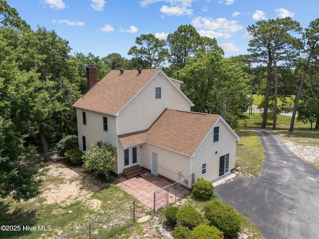 2544 Blake Trl, Wilmington, NC 28409 - view of property exterior featuring entry steps, a chimney, roof with shingles, view of wooded area, and driveway