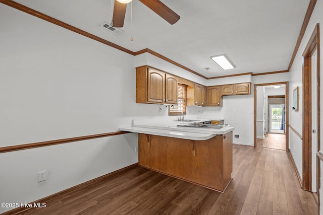 2544 Blake Trl, Wilmington, NC 28409 - kitchen featuring a peninsula, light countertops, wood finished floors, ceiling fan, and brown cabinets