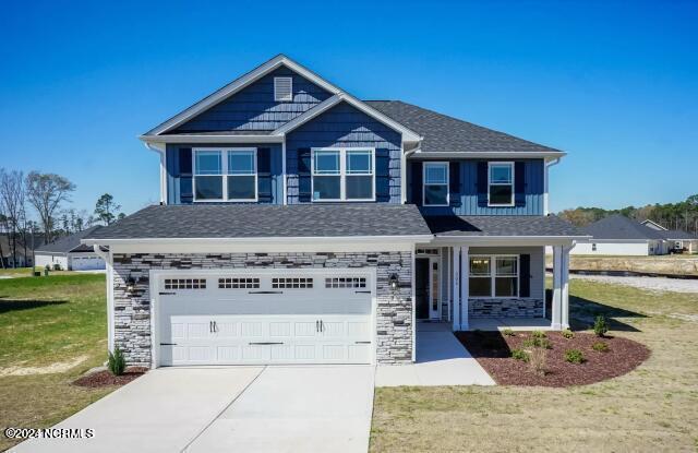 5705 Sloop Ct, New Bern, NC 28560 - craftsman house featuring a garage, a porch, a front lawn, concrete driveway, and stone siding