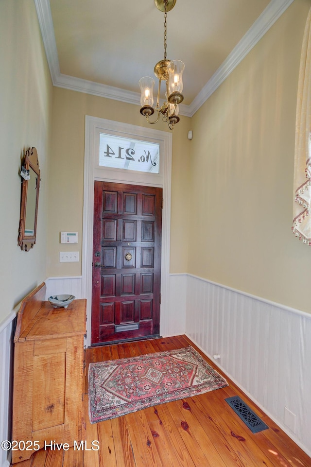 214 Nun St, Wilmington, NC 28401 - entryway with a chandelier, a wainscoted wall, wood finished floors, and ornamental molding
