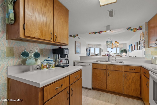 10300 Coast Guard Rd Unit E206Point, Emerald Villas, Emerald Isle, NC 28594 - kitchen with white appliances, light wood finished floors, light countertops, brown cabinets, and a chandelier
