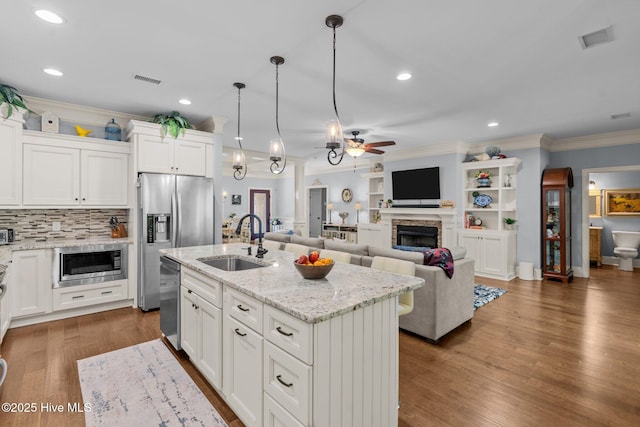 9134 Ocean Harbour Golf Club Rd SW, Calabash, NC 28467 - kitchen with stainless steel appliances, a ceiling fan, a fireplace, crown molding, and wood finished floors