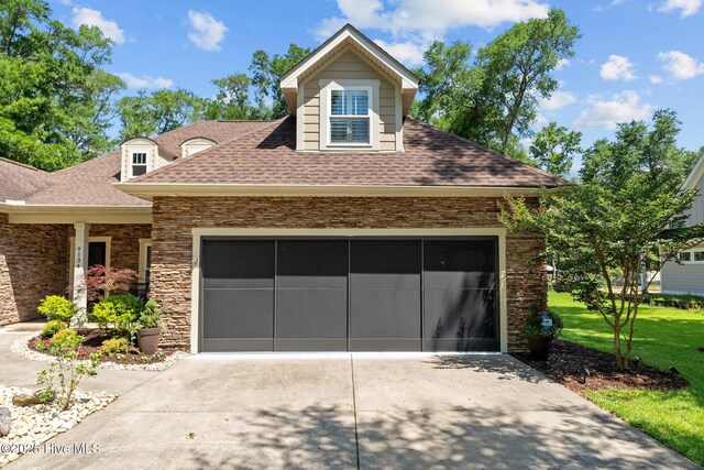9134 Ocean Harbour Golf Club Rd SW, Calabash, NC 28467 - view of front facade featuring concrete driveway, roof with shingles, stone siding, a garage, and a front yard