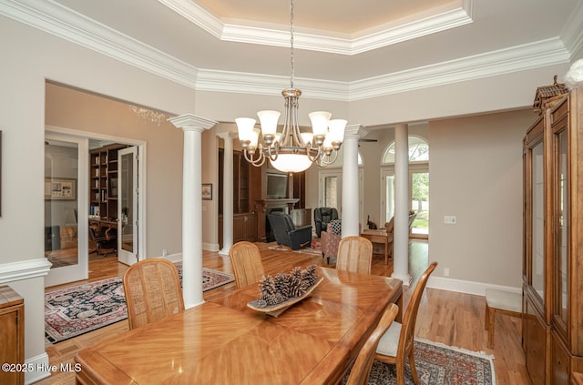 545 Gladstone Cir SW, Ocean Isle Beach, NC 28469 - dining room with ornate columns, a chandelier, a raised ceiling, ornamental molding, and light wood-style flooring