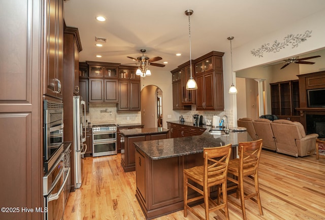545 Gladstone Cir SW, Ocean Isle Beach, NC 28469 - kitchen featuring ceiling fan, open floor plan, stainless steel appliances, arched walkways, and recessed lighting