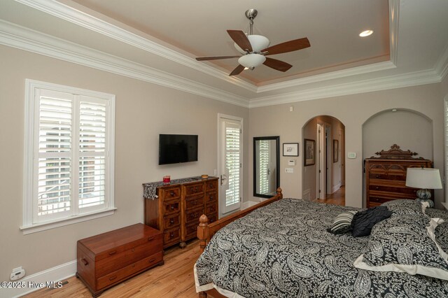 545 Gladstone Cir SW, Ocean Isle Beach, NC 28469 - bedroom with arched walkways, light wood-style floors, a tray ceiling, crown molding, and ceiling fan