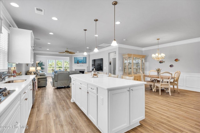 3236 Penzance Row, Wilmington, NC 28412 - kitchen featuring a ceiling fan, ornamental molding, a fireplace, a wainscoted wall, and light wood-style floors