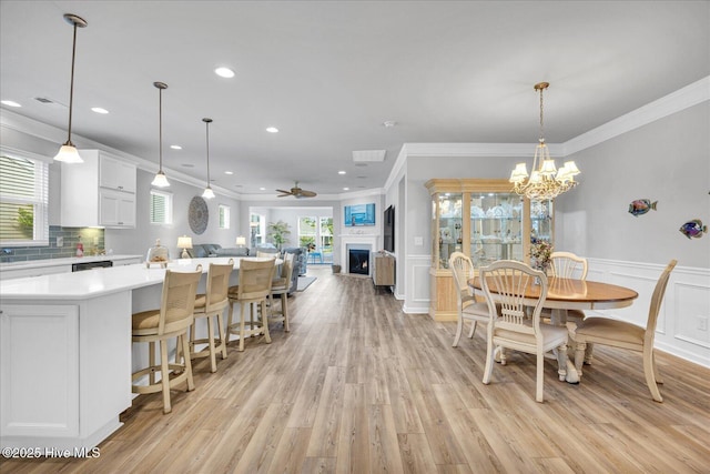 3236 Penzance Row, Wilmington, NC 28412 - dining area featuring ornamental molding, a fireplace, a decorative wall, light wood-type flooring, and a wainscoted wall