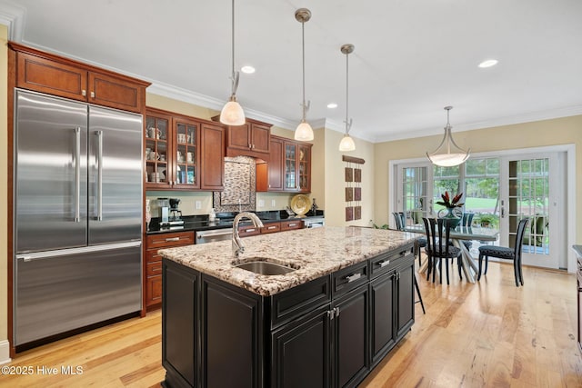 220 October Glory Dr, Wallace, NC 28466 - kitchen featuring built in fridge, light wood finished floors, crown molding, a center island with sink, and glass insert cabinets