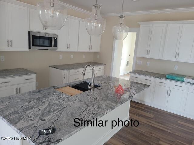 469 Fowler Manning Rd, Richlands, NC 28574 - kitchen with stainless steel microwave, a center island with sink, white cabinets, light stone countertops, and crown molding