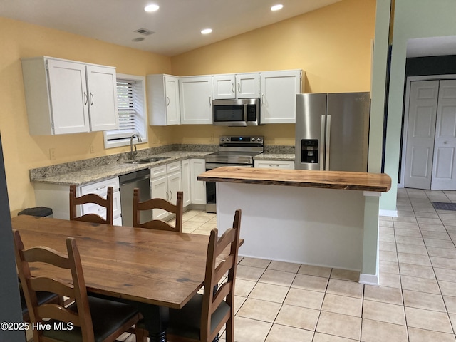 7417 Coker Ct, Wilmington, NC 28411 - kitchen featuring appliances with stainless steel finishes, light tile patterned flooring, white cabinetry, wooden counters, and a kitchen island