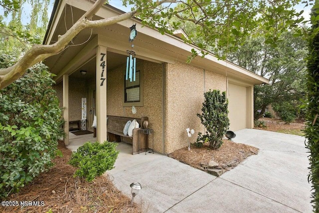 7417 Coker Ct, Wilmington, NC 28411 - view of property exterior with concrete driveway, stucco siding, a porch, and an attached garage