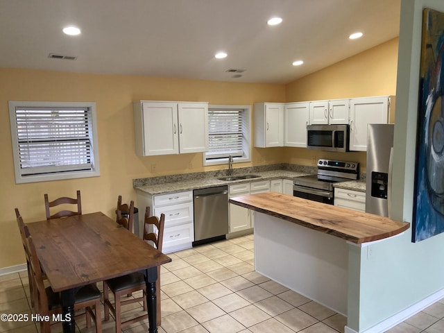 7417 Coker Ct, Wilmington, NC 28411 - kitchen featuring stainless steel appliances, wooden counters, white cabinets, light tile patterned floors, and recessed lighting