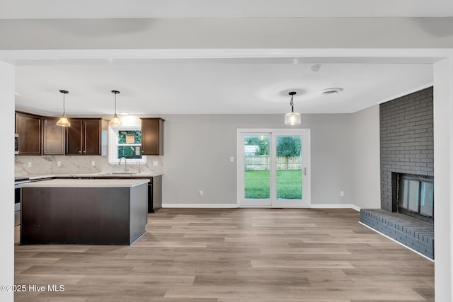 411 Cardinal Dr, Jacksonville, NC 28546 - kitchen with dark brown cabinets, light wood finished floors, light countertops, backsplash, and plenty of natural light