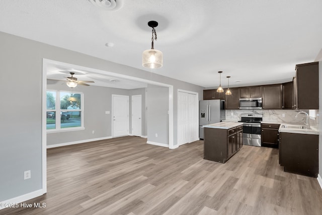 411 Cardinal Dr, Jacksonville, NC 28546 - kitchen with appliances with stainless steel finishes, dark brown cabinets, decorative backsplash, light countertops, and a kitchen island