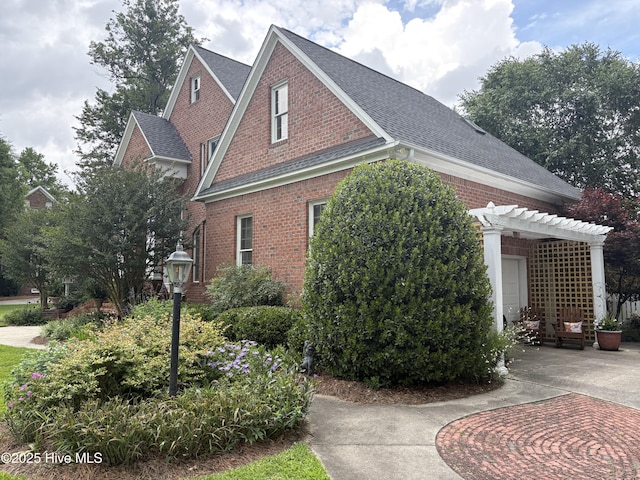 1009 Colleton Way, New Bern, NC 28562 - view of property exterior with brick siding, a pergola, and a shingled roof