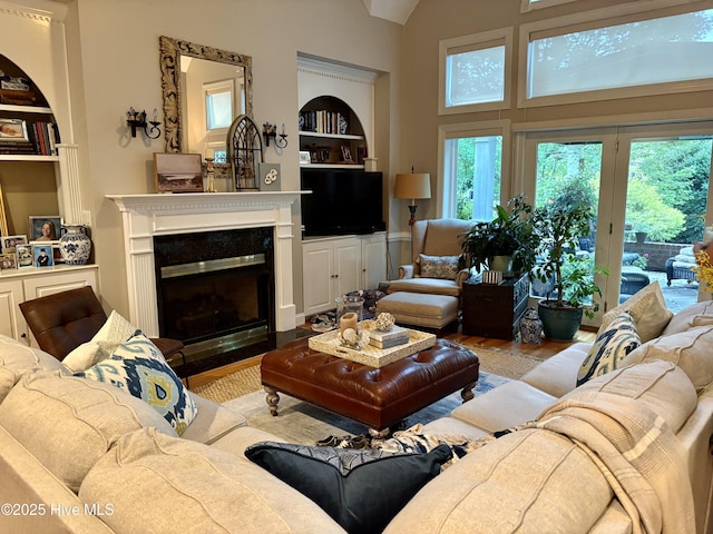 1009 Colleton Way, New Bern, NC 28562 - living room featuring built in shelves, a glass covered fireplace, wood finished floors, and a towering ceiling