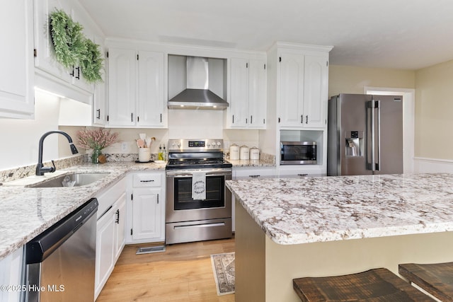 84 White Pine Rd, Lake Waccamaw, NC 28450 - kitchen with wall chimney exhaust hood, appliances with stainless steel finishes, light wood-style floors, white cabinets, and light stone counters