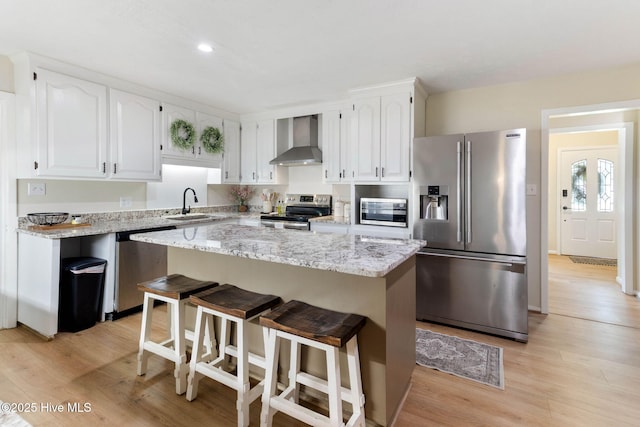 84 White Pine Rd, Lake Waccamaw, NC 28450 - kitchen with stainless steel appliances, wall chimney range hood, white cabinetry, light wood-style floors, and a kitchen island