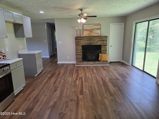 527 W College St, Warsaw, NC 28398 - unfurnished living room with ceiling fan, a textured ceiling, dark wood finished floors, and a wood stove