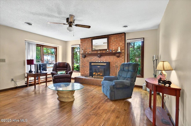 163 NW 9th St, Oak Island, NC 28465 - living area with healthy amount of natural light, a brick fireplace, a ceiling fan, wood finished floors, and a textured ceiling