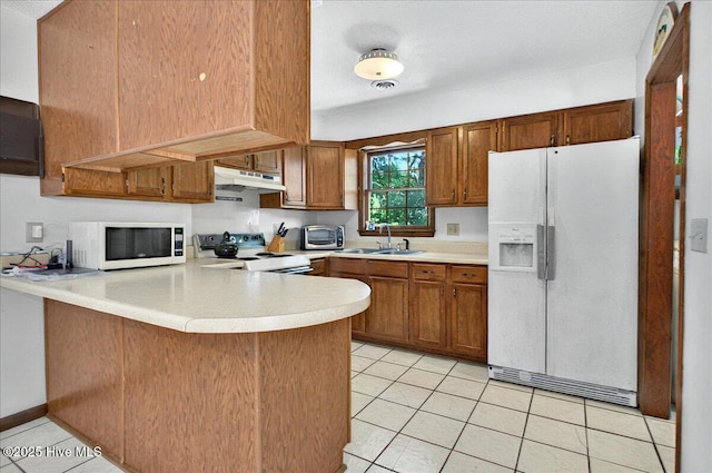 163 NW 9th St, Oak Island, NC 28465 - kitchen with white appliances, under cabinet range hood, a peninsula, light countertops, and light tile patterned floors