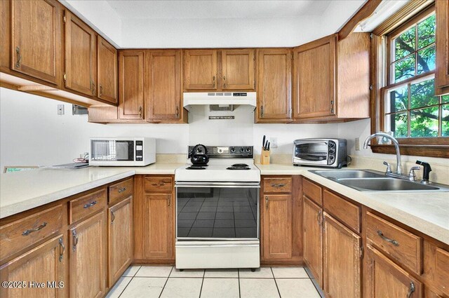 163 NW 9th St, Oak Island, NC 28465 - kitchen featuring white appliances, under cabinet range hood, brown cabinets, and light tile patterned floors